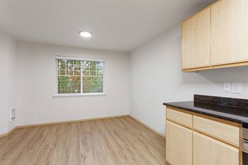 A kitchen with wooden cabinets and a window with blinds.